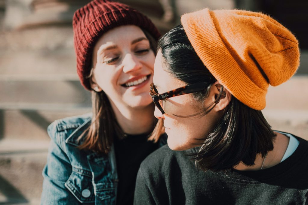 Two women sitting outside wearing winter hats