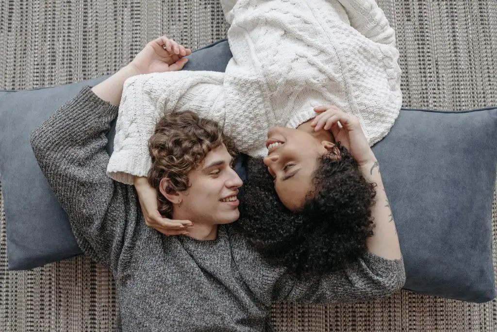 Couple lying together and laughing, representing connection and healing through trauma-informed couples therapy Oakland at Wildhaven Therapy